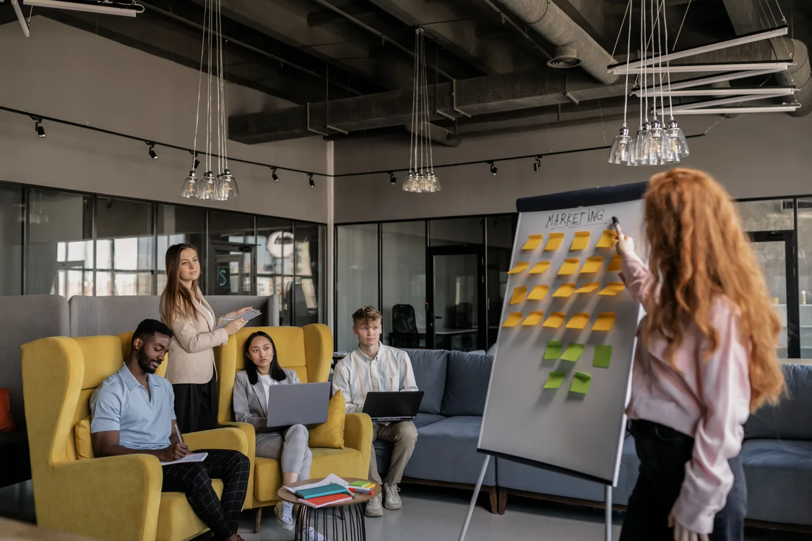 A diverse team collaborating on marketing strategy using a whiteboard with sticky notes. Digital marketing campaign questions: boundaries, timing, channels and attribution