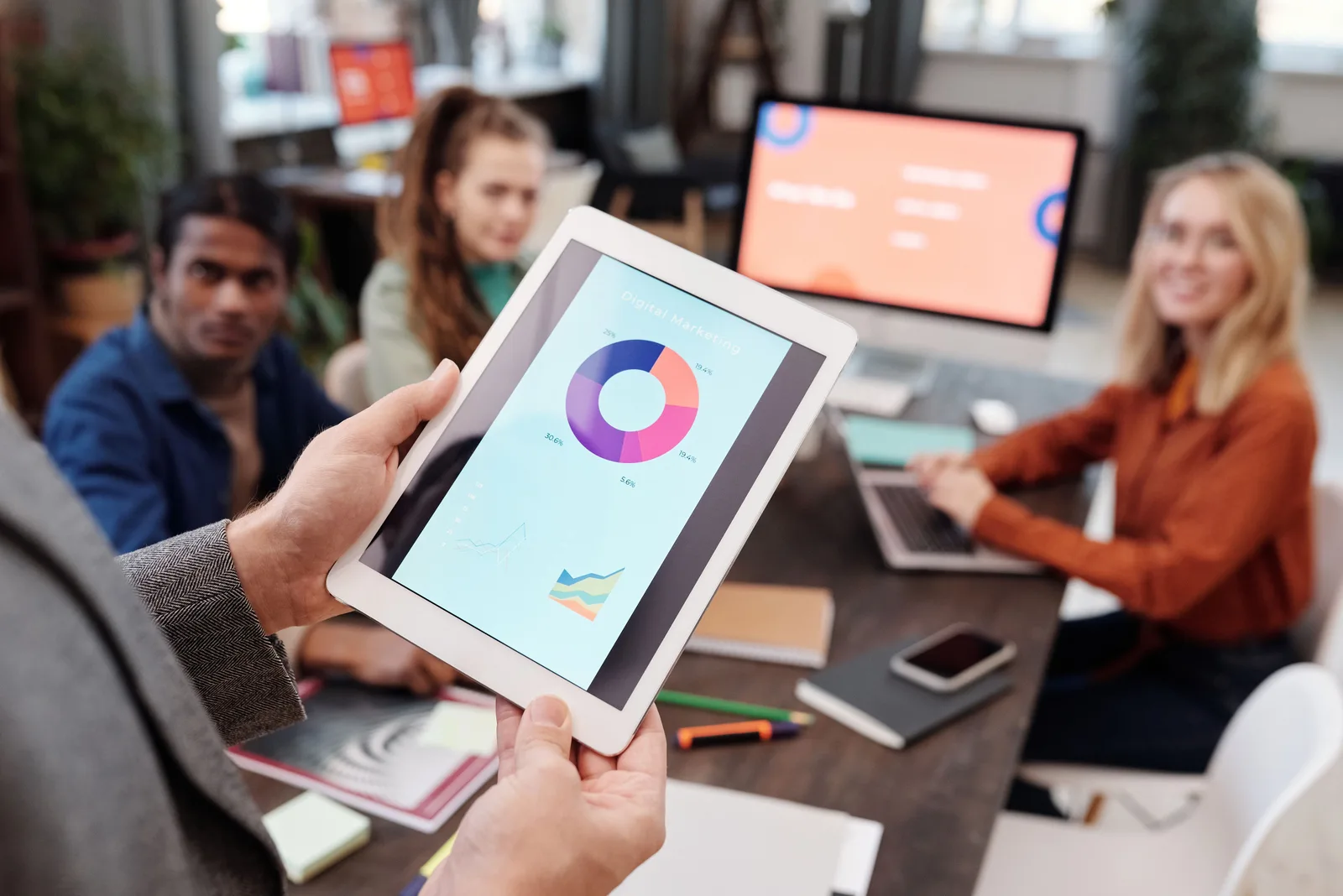 Business team using a tablet to analyze digital marketing data with charts in an office setting. Digital marketing agencies: choosing and governing