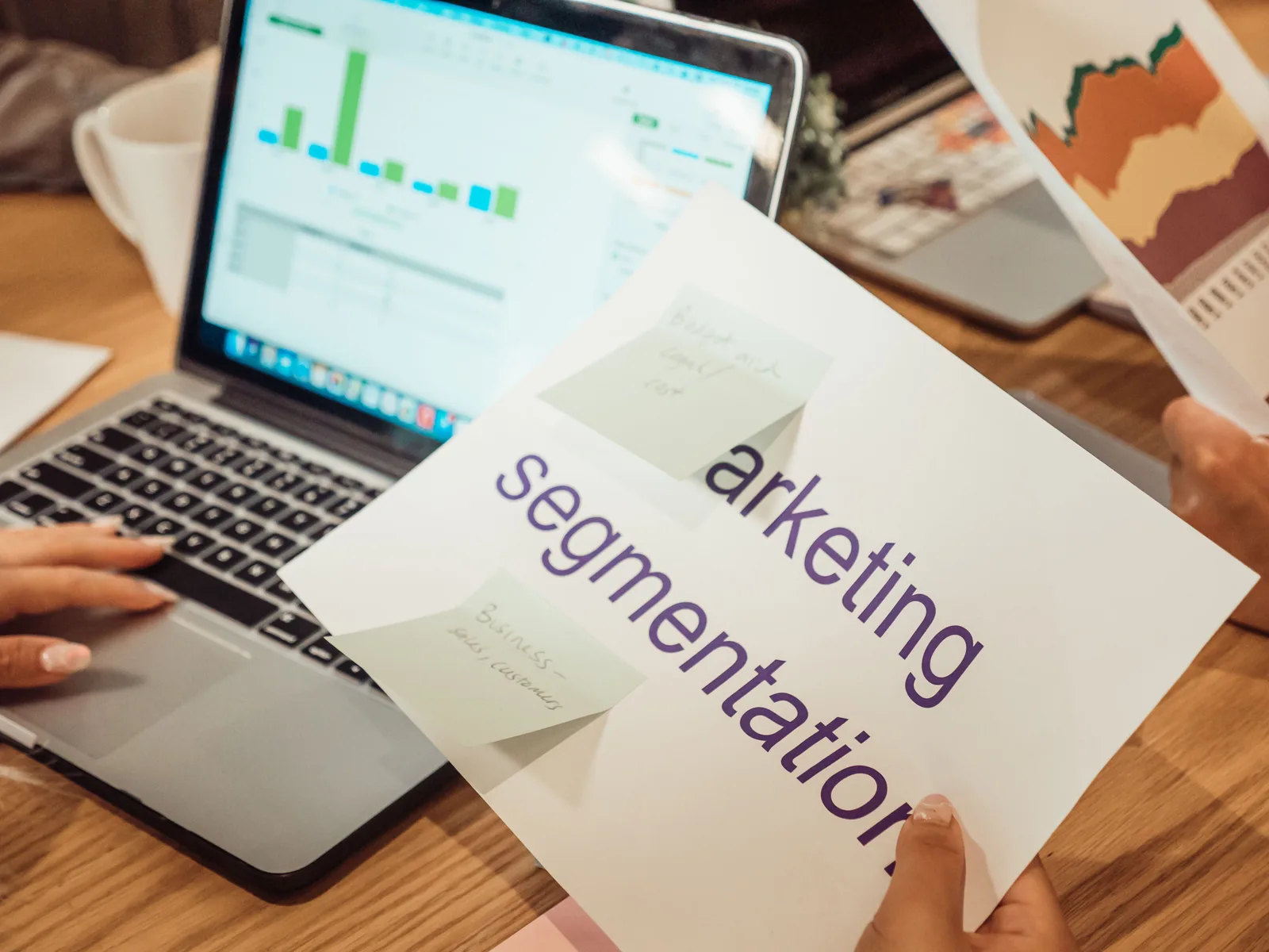 A modern workspace showing hands analyzing marketing data on a laptop and paper documents. Digital marketing platforms alternatives, one decision at a time