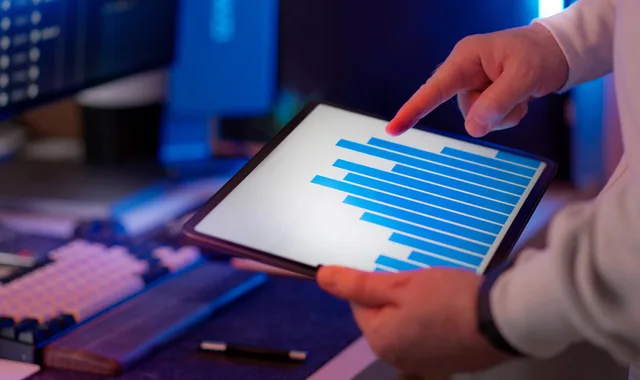 Business professional analyzing bar chart on tablet in office setting, highlighting data insights. Digital marketing platforms comparison: what to keep and what to drop