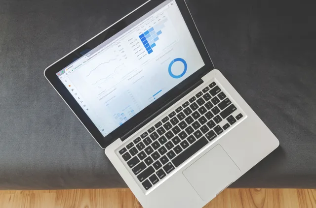 Overhead view of a laptop showing data visualizations and charts on its screen. Digital marketing platforms pricing from the buyer side and the seller side