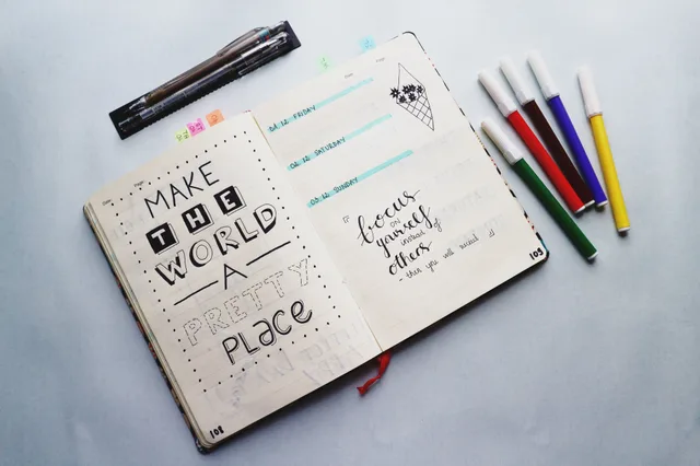 Open bullet journal with quotes and colorful markers for planning and creativity. How to define and record omnichannel marketing benchmarks